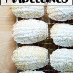 Lemon madeleines dusted in powdered sugar on a cooling rack.