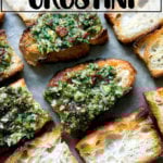 Sun-dried tomato and spinach pesto spread on crostini on a sheet pan.
