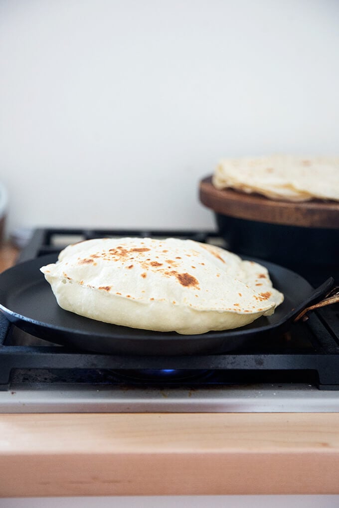 A homemade flour tortilla cooking in a skillet stovetop.