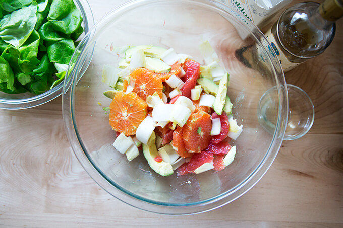A bowl of citrus segments, avocado, endive, sea salt, and white balsamic vinegar.