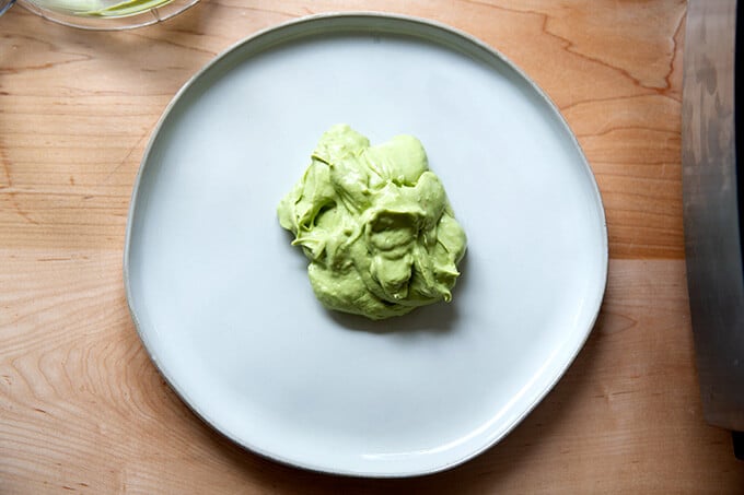A platter with a spoonful of avocado cream in the center.