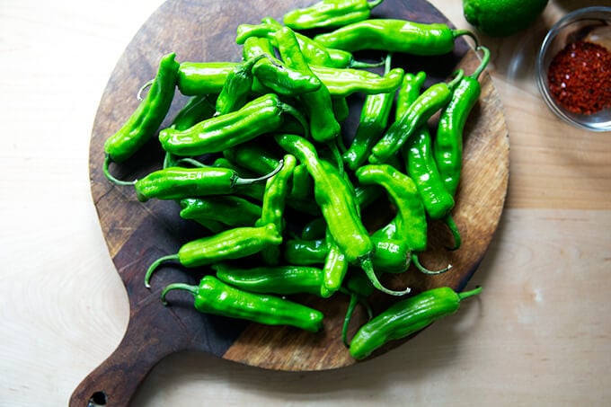 A board topped with shishito peppers.