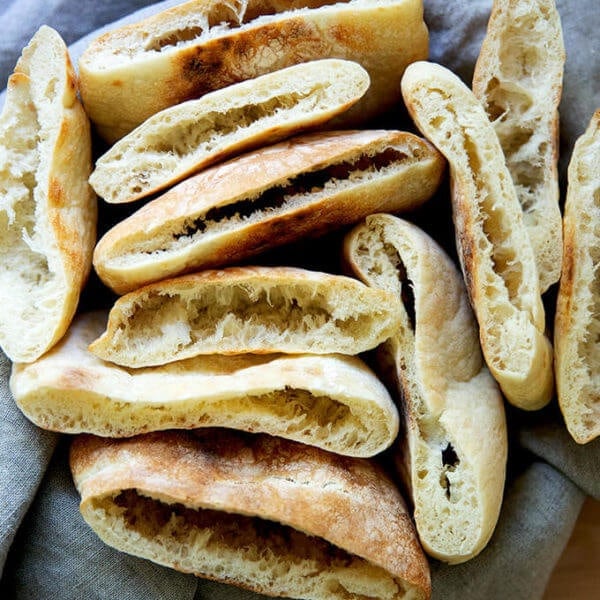 A bowl of cut open rounds of pita bread.