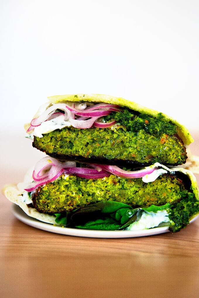 A halved falafel burger on a plate.