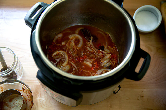 An Instant pot holding water, tomatoes, onions, and chipotle in adobo sauce.