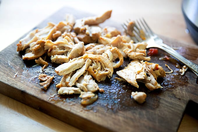 Shredded chicken tinga on a board.
