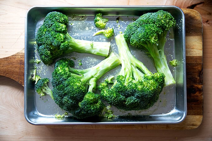 Two halved heads of broccoli on a sheet pan.