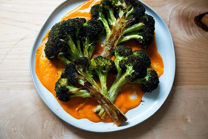 Roasted broccoli halves on a plate spread with tomato sauce.