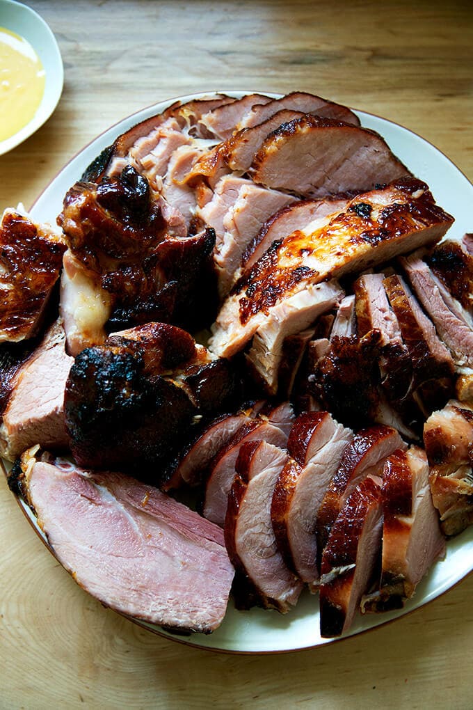 A carved brown sugar glazed ham on a platter.