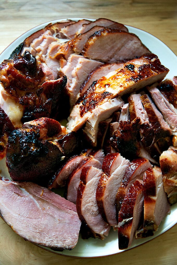 A carved brown sugar glazed ham on a platter.