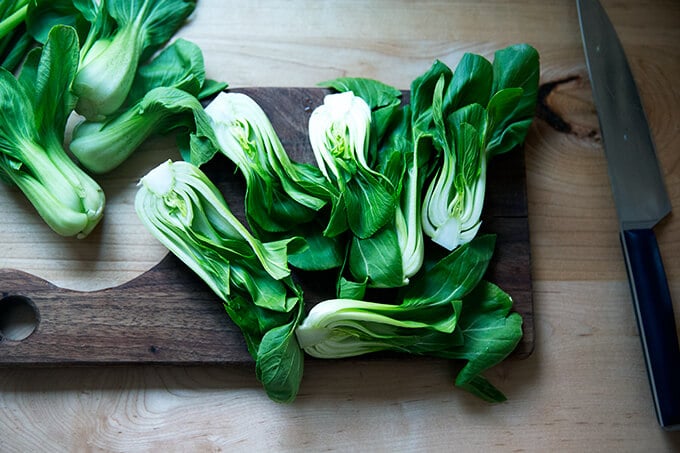 A board topped with halved bok choy.