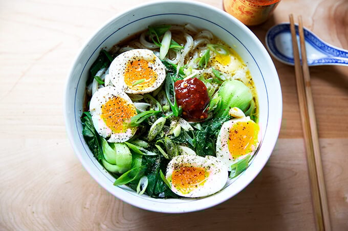 A bowl of life changing udon noodles with bok choy and soft boiled eggs and Sambal Oelek. 