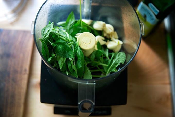 A food processor with garlic and basil.