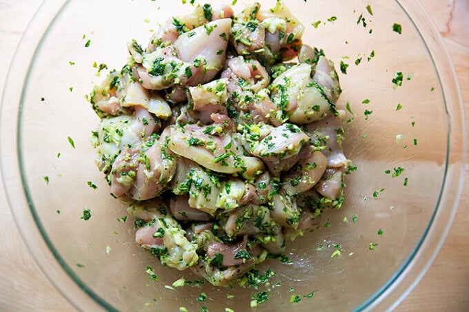 A bowl of chicken marinated with garlic and basil.