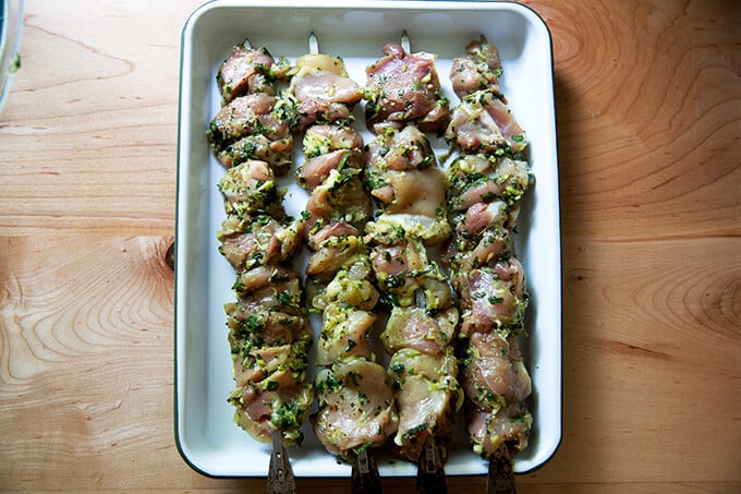 Chicken souvlaki skewered on a tray.