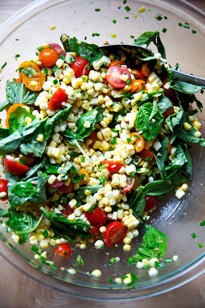 A raw corn salad made with tomatoes and lots of herbs all tossed together in a bowl.