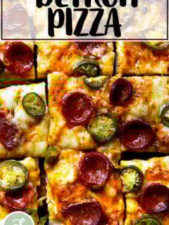 A sliced pepperoni and pickled jalapeño Detroit-style pizza on a board.