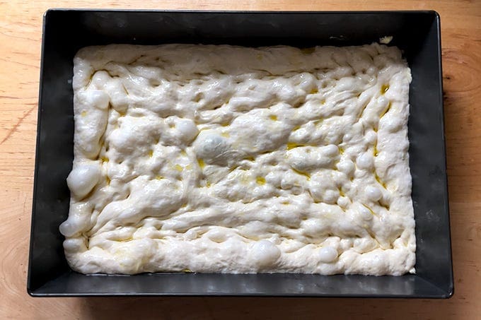 Unbaked Detroit-style pizza dough stretched edge to edge in a 10x14-inch pan. 