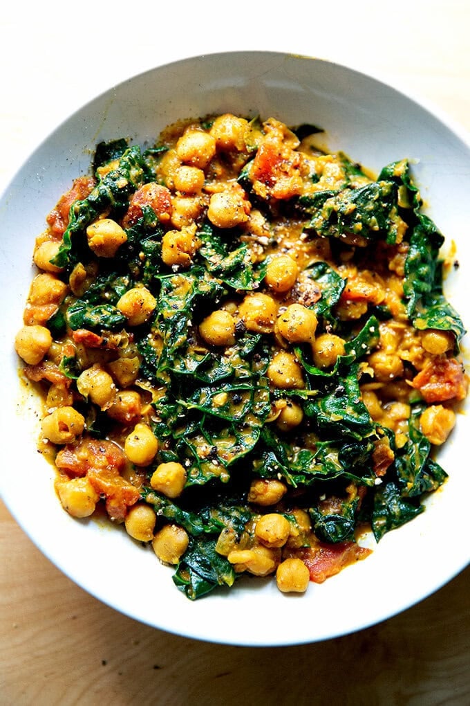 A bowl of spicy chickpeas with tomatoes and kale.