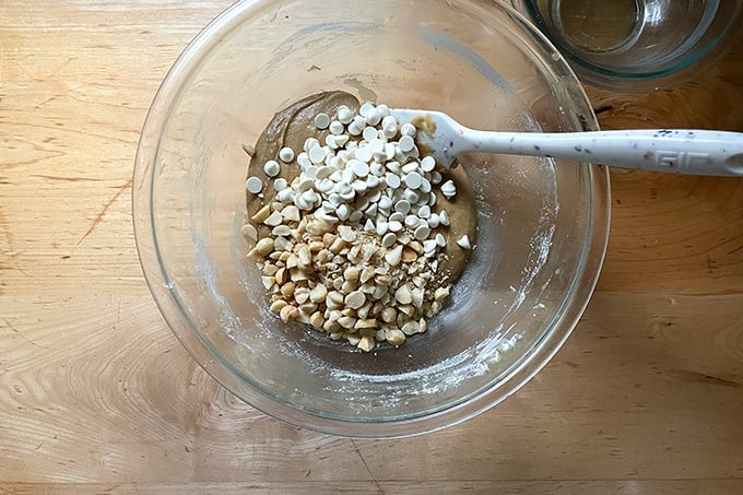 Adding the white chocolate and macadamia nuts to the cookie batter.