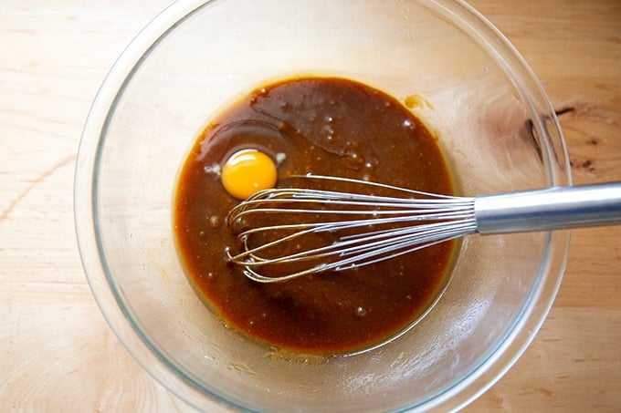 Adding the egg to the wet ingredients to make ginger bread cookie bars in a large bowl.