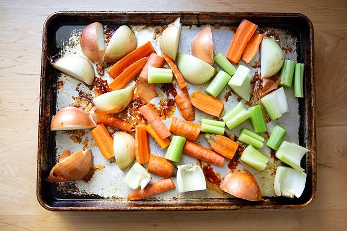 Carrots, onions, and celery added to a sheet pan.