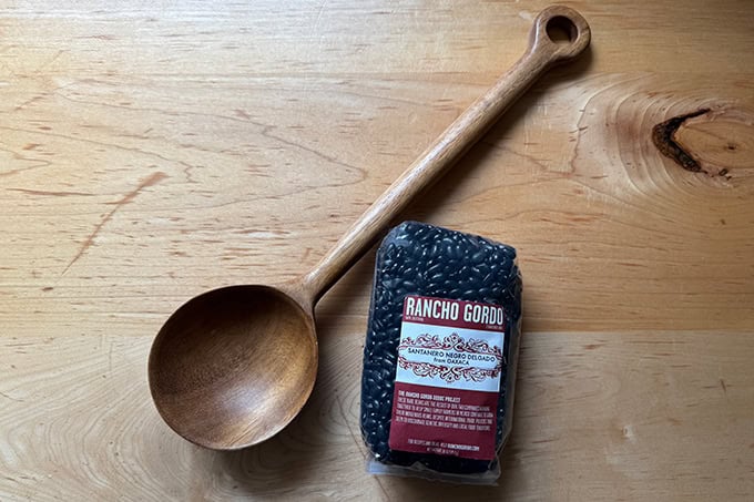 A bean spoon aside a bag of beans.