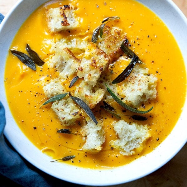 A bowl of roasted butternut squash soup topped with croutons and fried sage.
