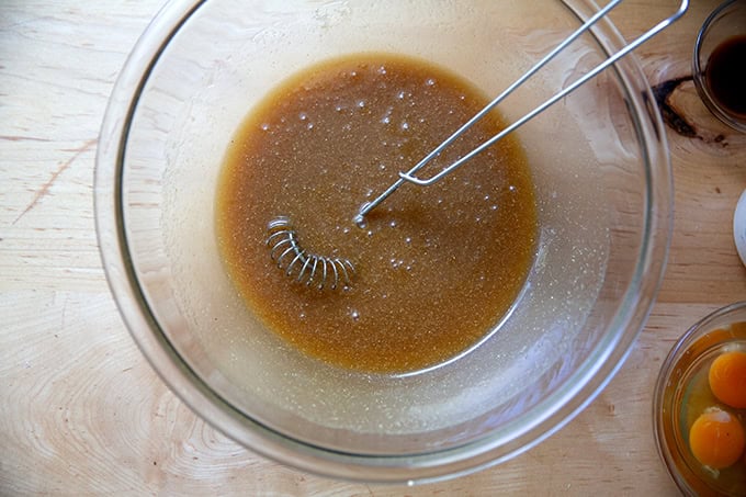 A bowl with brown sugar, maple syrup, melted butter, cornmeal and salt whisked together.