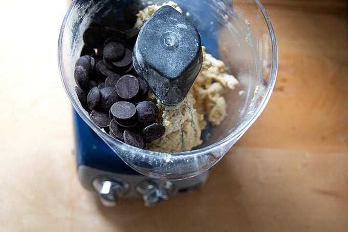 An Ankarsrum mixer filled with chocolate chip cookie dough, the chocolate chips just added.