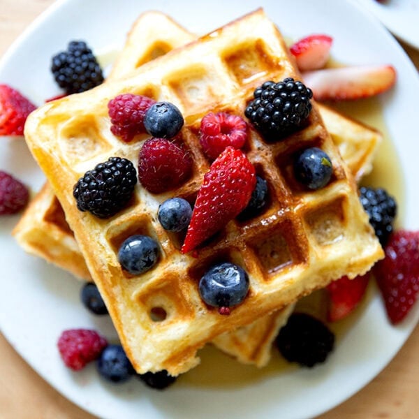 A plate of sourdough discard waffles topped with berries and syrup.