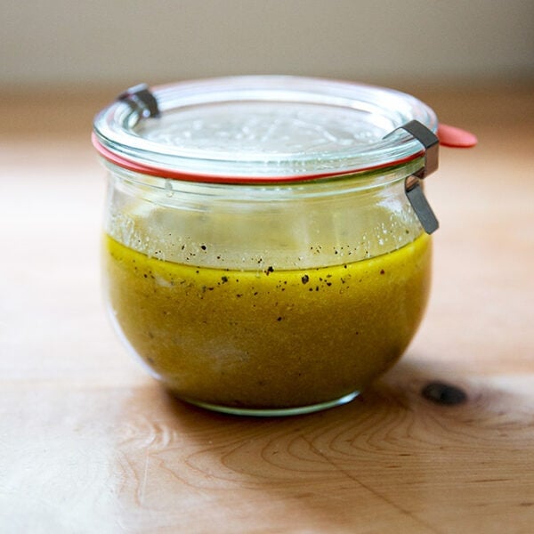 A jar of Greek salad dressing on a countertop.