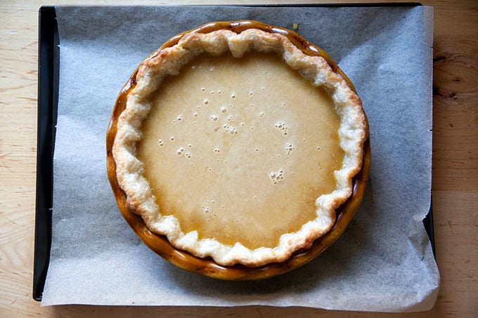 A parbaked pie shell on a sheet pan filled with salted maple pie filling, not yet baked.
