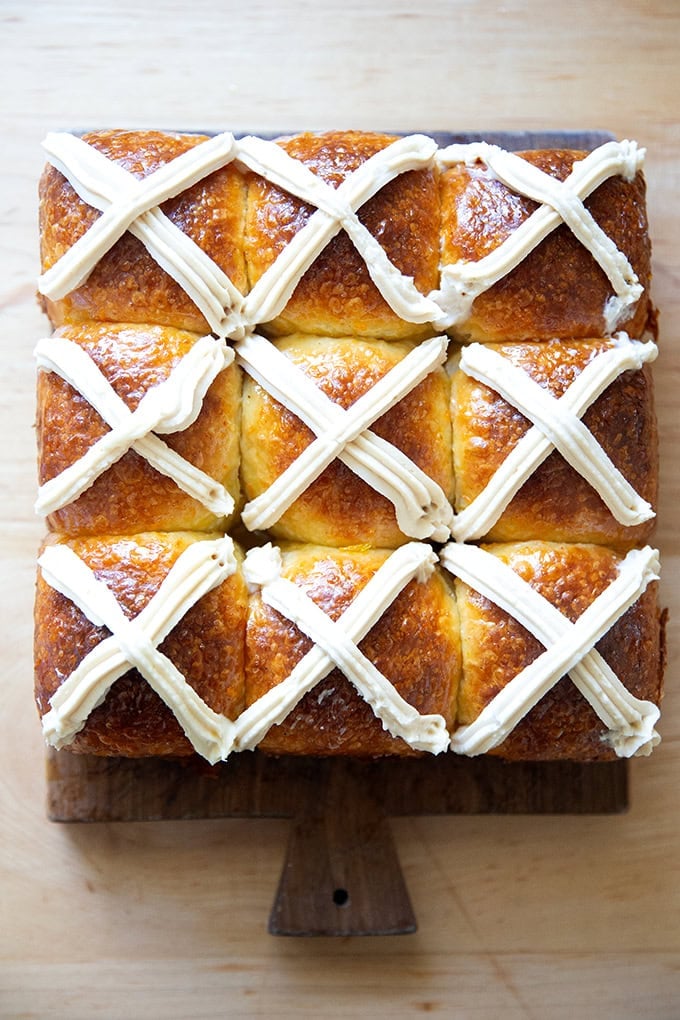 Nine hot cross buns on a serving board.
