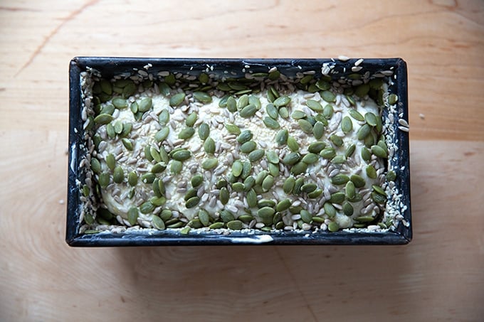 Three seed bread dough rising in a loaf pan.