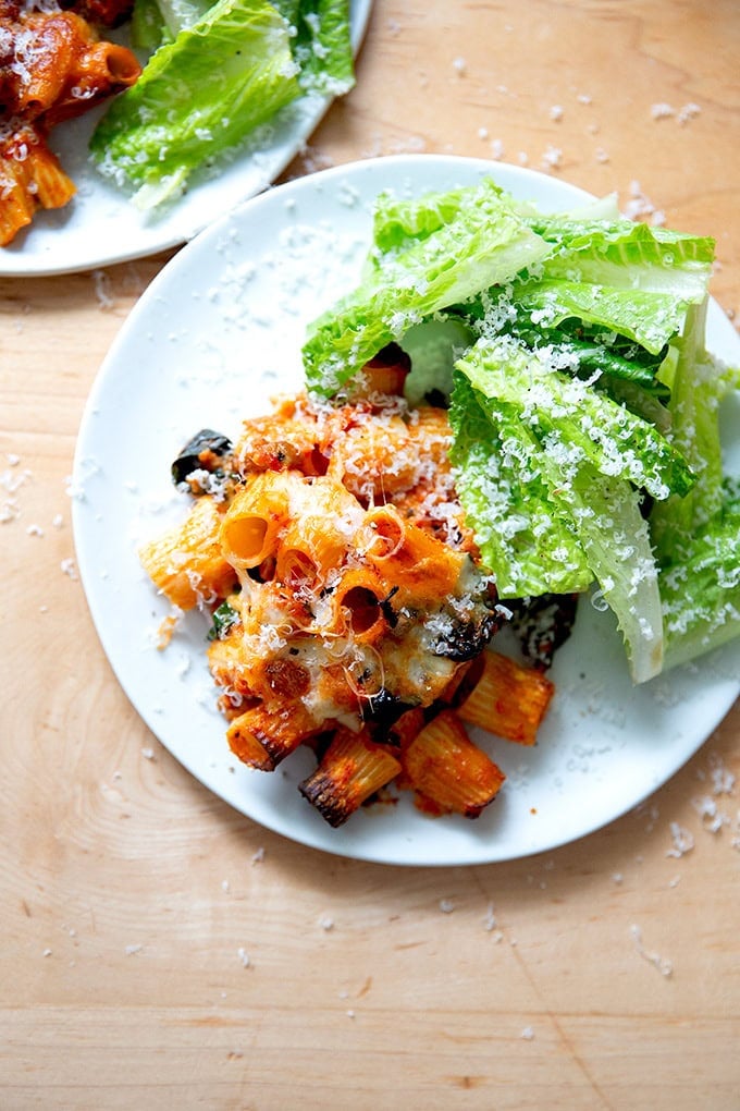 A plate of baked pasta aside salad.