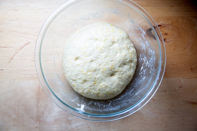 A glass bowl filled with risen hot cross bun dough.