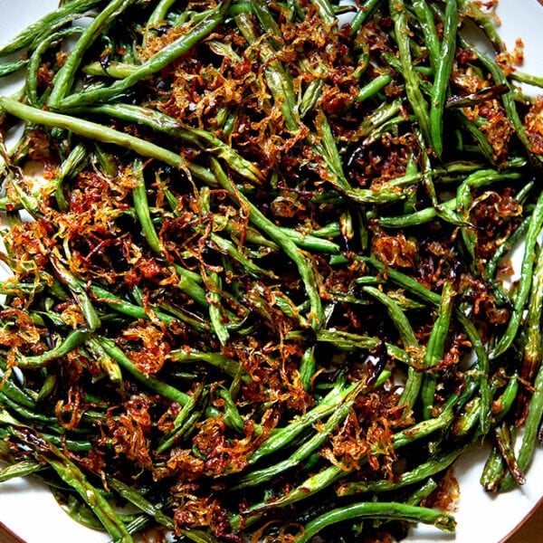 A platter of roasted green beans with crispy fried shallots.