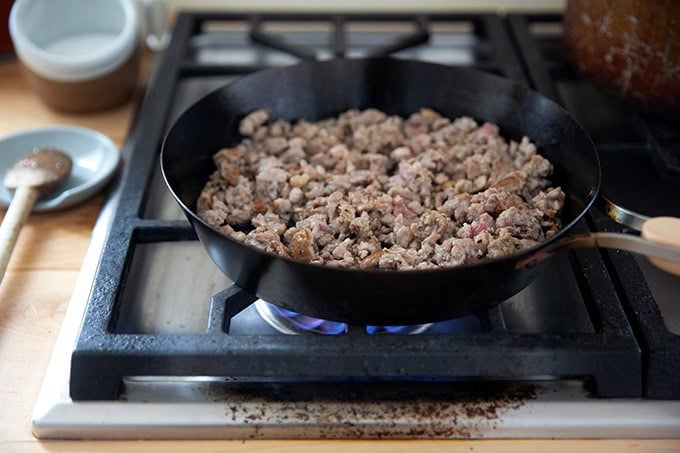 A skilled filled with browned sausage on the stovetop.