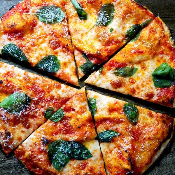A cut gluten-free Margherita pizza on a cutting board.