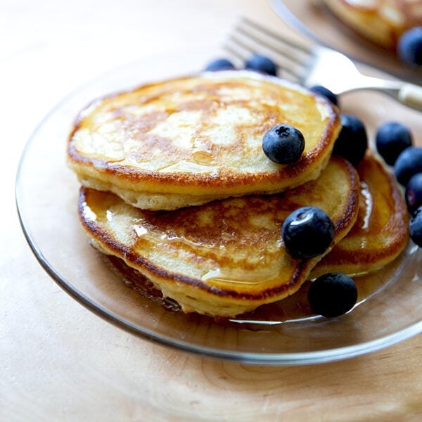 A plate of sourdough discard pancakes topped with syrup and blueberries.