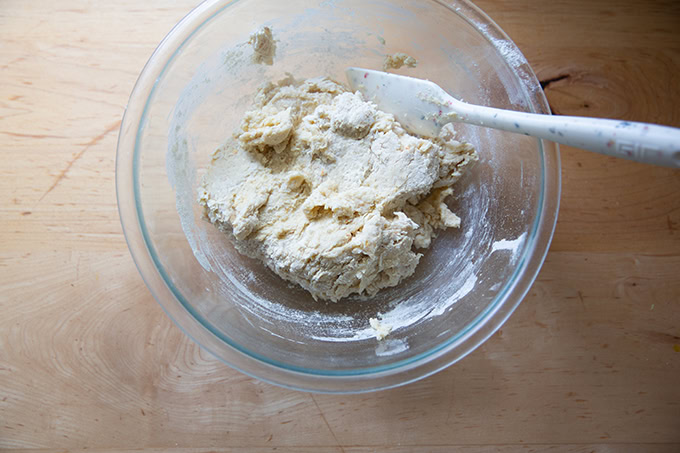 A bowl of hot cross bun dough mixed with a spatula.