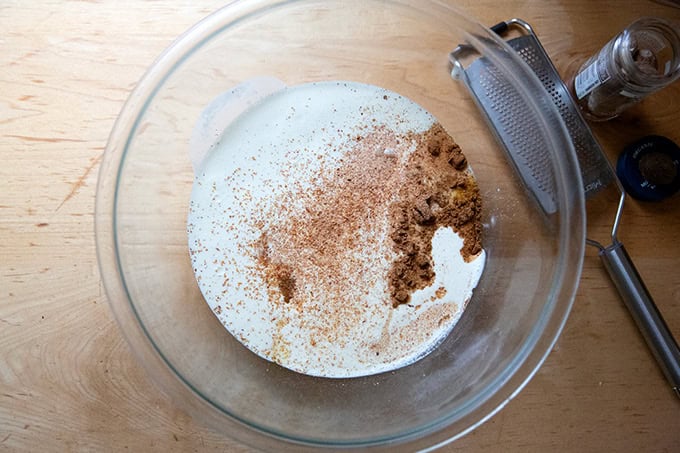 A large bowl filled with heavy cream, eggs, sugar, salt and spices for roasted butternut squash pie.