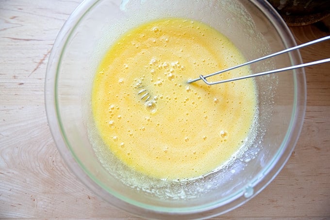 A bowl filled with the wet ingredients to make brownies whisked together.