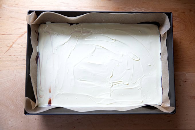 A layer of melted white chocolate spread over a layer of dark chocolate in a 10x14-inch pan.