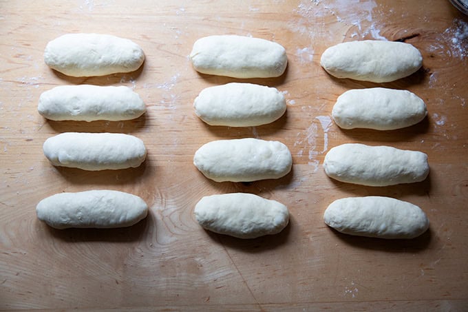 Twelve 4 inch oval rounds of dough resting on a countertop.