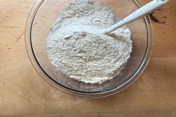 A bowl of water, salt, sourdough starter and flour, not yet mixed together.