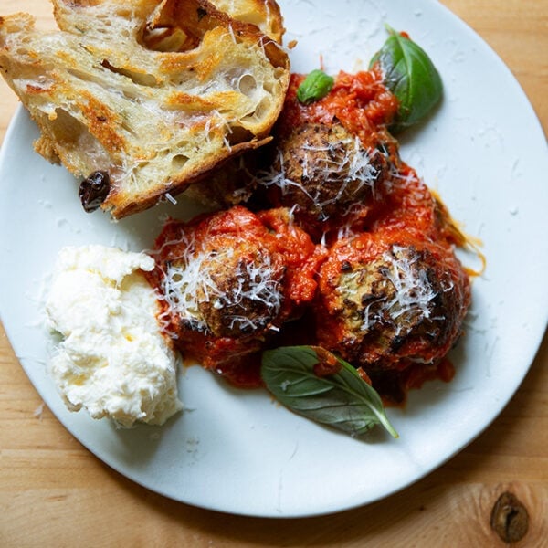 A plate of eggplant meatballs aside bread and ricottta.