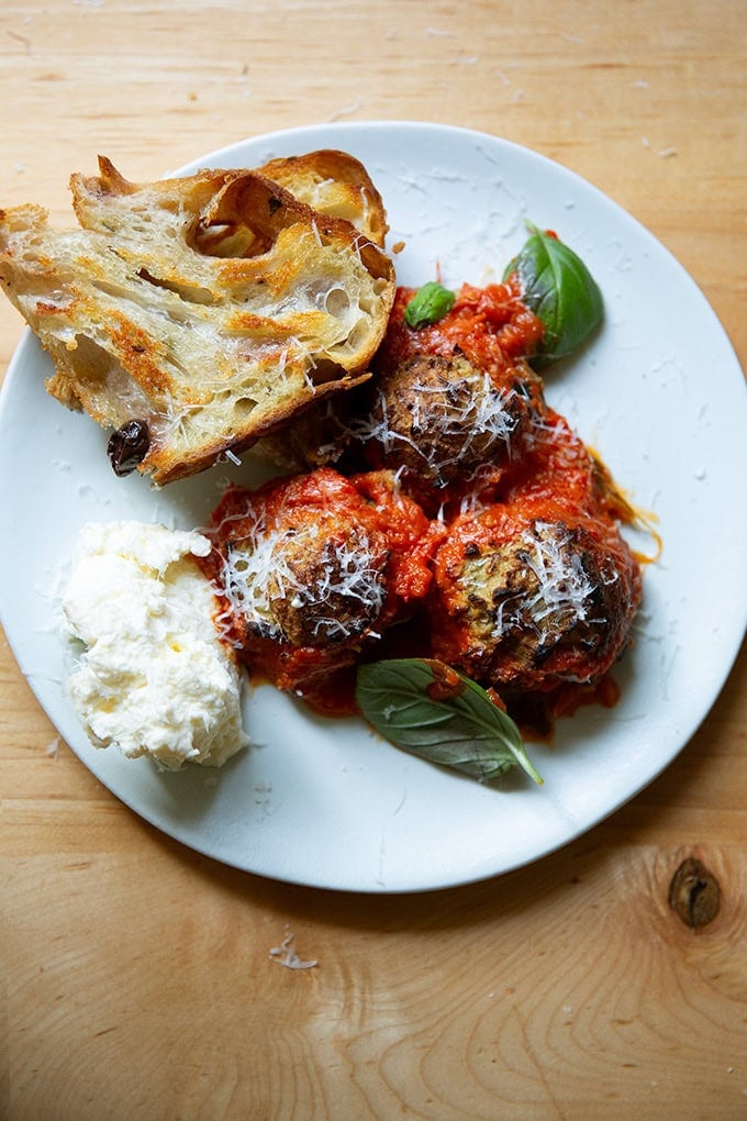 A plate of eggplant meatballs aside bread and ricottta.