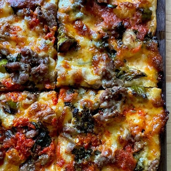 Grandma-style pizza on a cutting board cut into square slices.